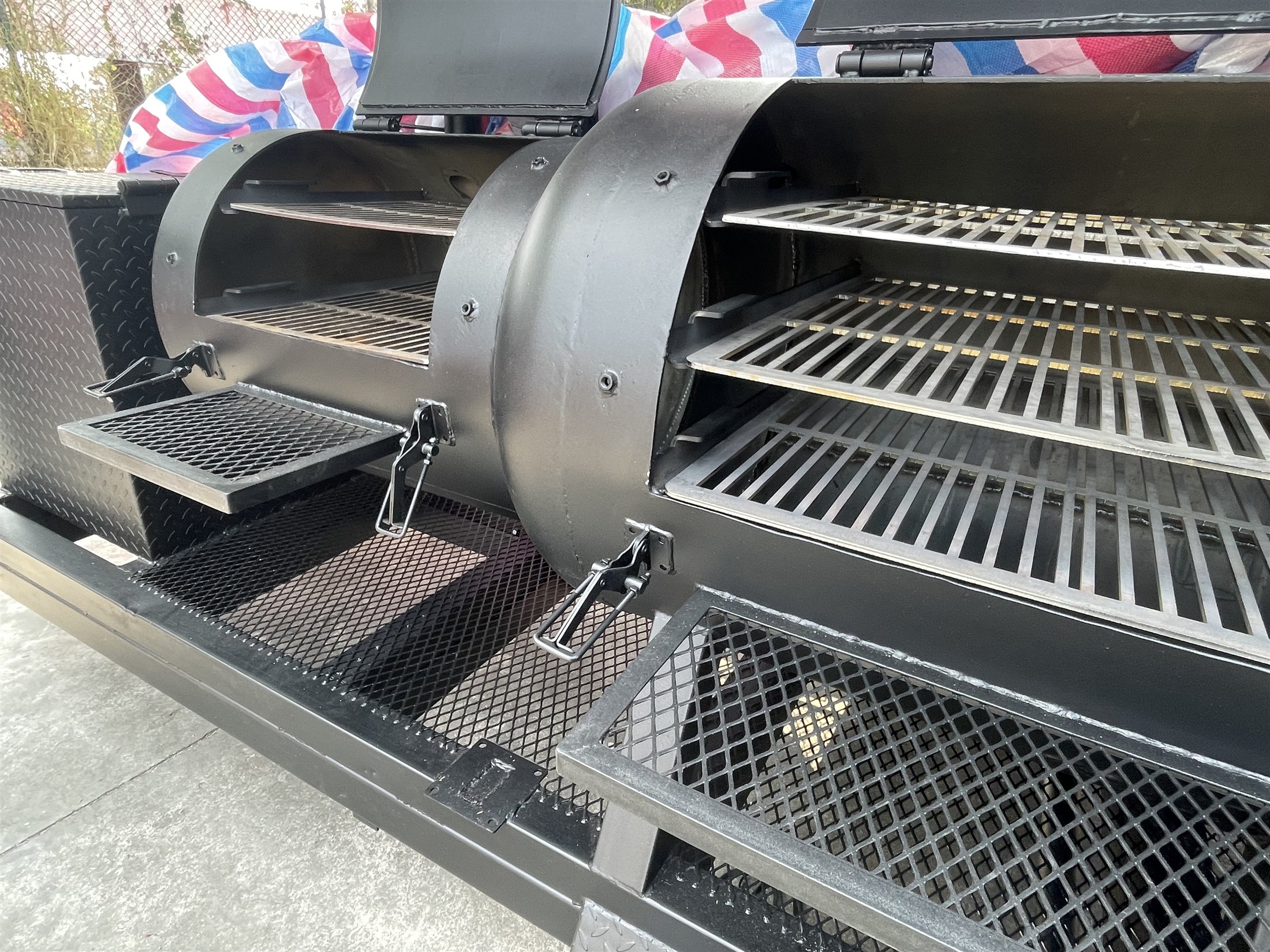 Open smoker chambers and cooking racks on a custom trailer